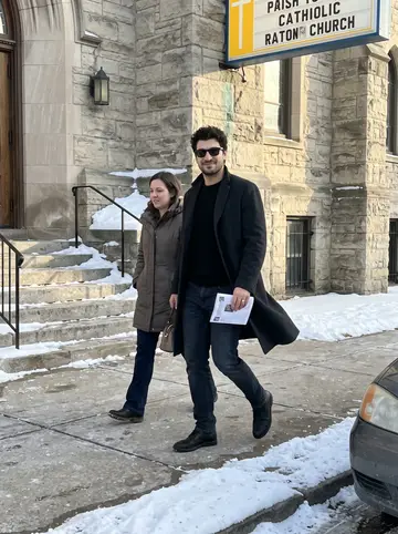 Ostap, AI character: outside a small old Catholic church in a Cleveland neighborhood after Sunday Mass, snow piled along the curb