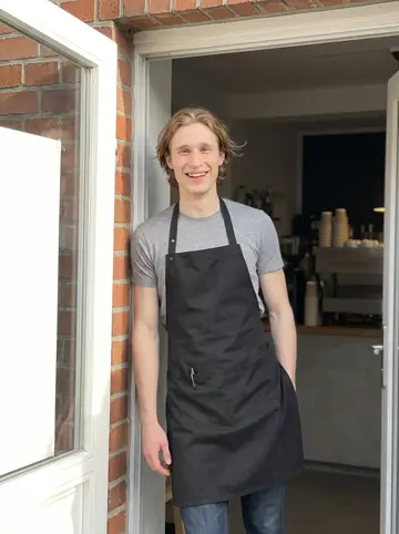 Linus, AI character: outside the specialty roastery on a quiet Hamburg side street after the morning rush, standing in the open…