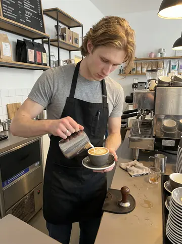 Linus, AI character: behind the espresso bar at the Hamburg roastery during a busy weekday morning, cups stacked beside the…