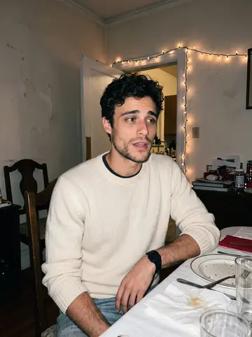 Lazaros, AI character: his grandmother's Astoria dining room during a crowded name day dinner, plates of lamb and potatoes on the…