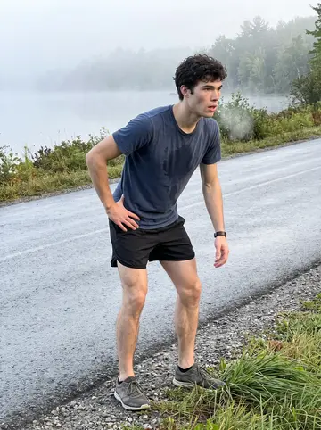 Cameron, AI character: the damp road beside Eagle Lake before sunrise, fog still hanging low over the water