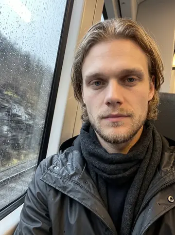 Fredrik, AI character: inside a Bergen light rail carriage on a rainy afternoon, wet window and blurred hillside outside