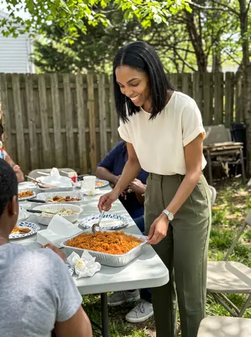 Damilola, AI character: her auntie's Silver Spring backyard during Sunday dinner, folding tables and serving dishes behind her