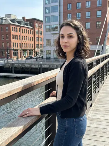 Patricia, AI character: the Providence pedestrian bridge near the river after clinical orientation, downtown buildings and water…