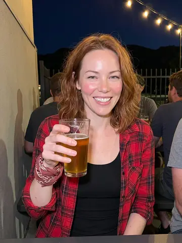 Freya, AI character: a crowded Boulder brewery patio after dark, string lights and dark foothill outlines behind the tables