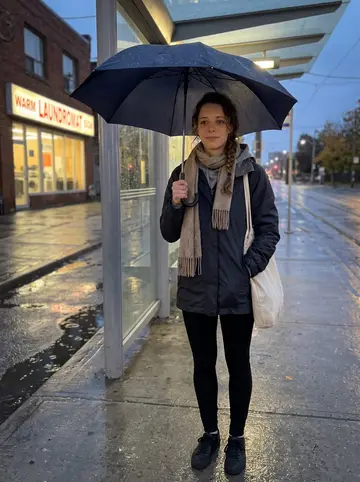 Ruby, AI character: outside a Toronto streetcar stop after her swim club shift, wet pavement and a laundromat glowing across…