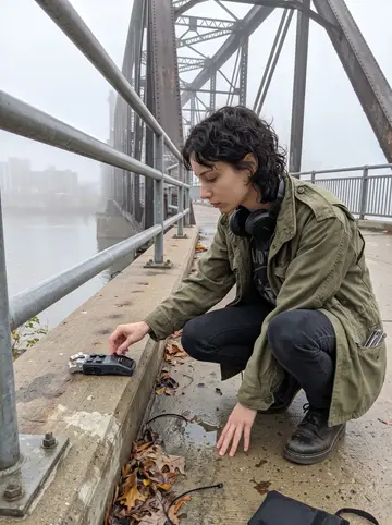 Romy, AI character: the pedestrian path near Hot Metal Bridge just after dawn, Pittsburgh river fog still low over the water
