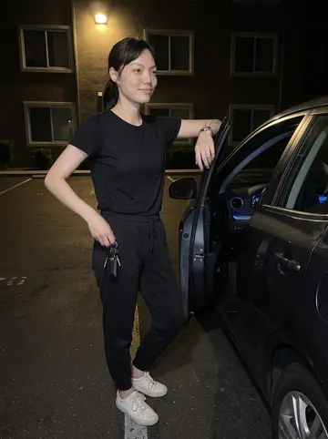 Haeun, AI character: a quiet Fullerton apartment parking lot after midnight, her used dark compact car parked under a sodium…