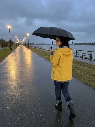 Sophie, AI character: the Mississippi riverfront levee at damp autumn dusk, streetlamps reflecting on wet pavement and low…