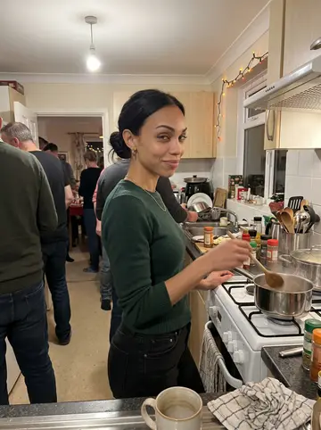 Débora, AI character: crowded family kitchen on Christmas Eve with a pot of bacalhau on the stove and holiday lights around the…