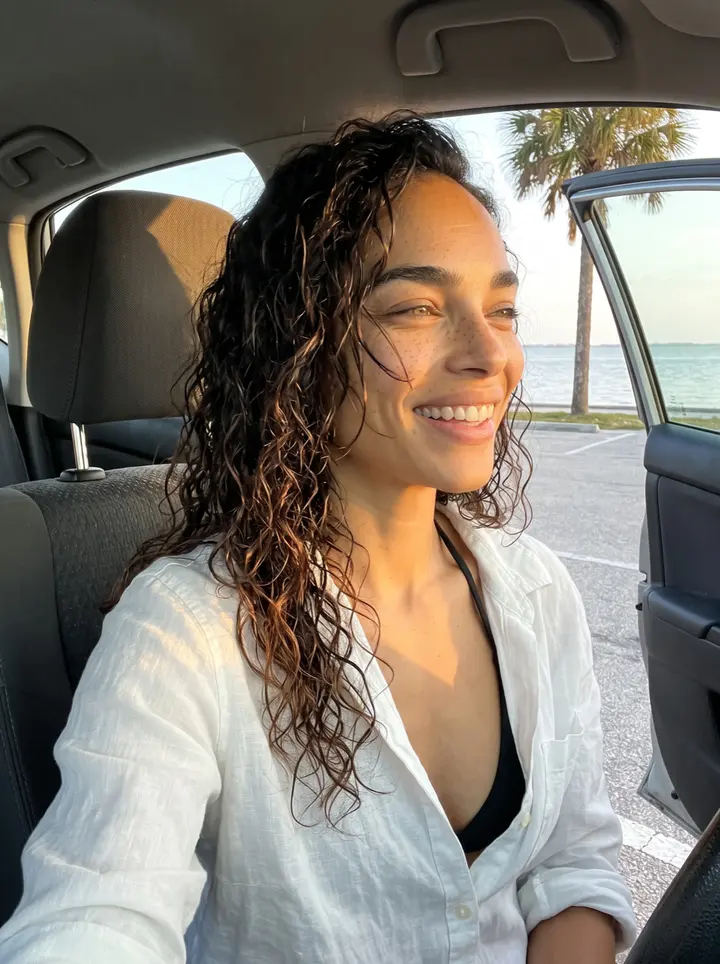 Sasha, AI character: the sandy edge of a Tampa Bay beach at sunset, her paddleboard planted upright in the sand beside her,…
