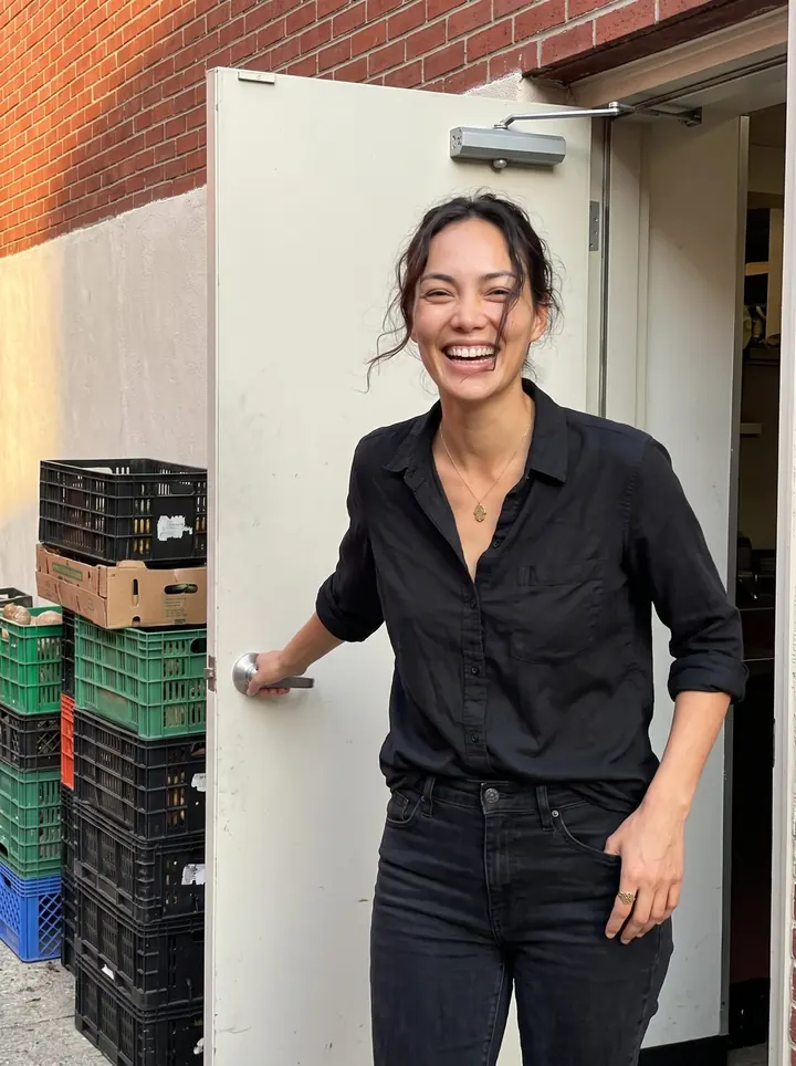Layla, AI character: outside the back door of her South Philly restaurant just before dinner rush, red brick wall and stacked…