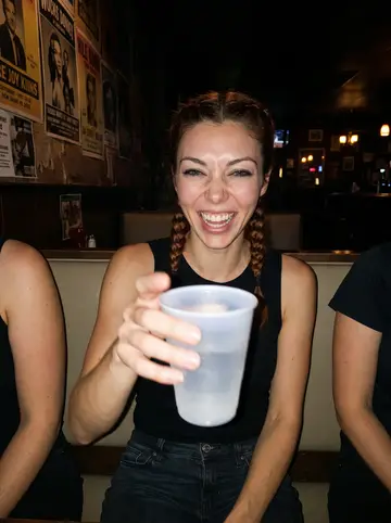 Alana, AI character: crowded Northeast Minneapolis dive bar after a Saturday roller derby bout, squeezed into a booth with…
