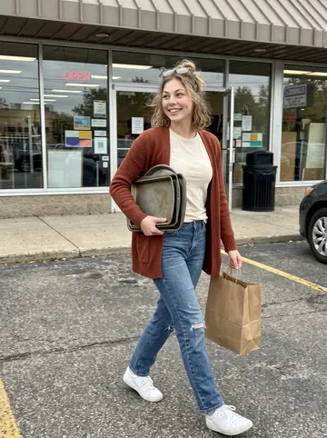 Samantha, AI character: outside a small thrift store in Clintonville, Columbus, carrying a stack of vintage baking pans and a…