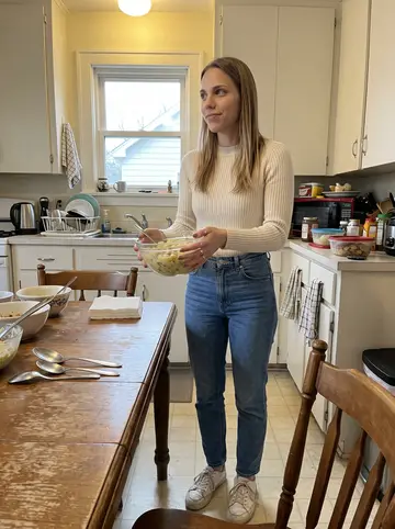 Andrea, AI character: her grandmother's kitchen in Milwaukee during a birthday lunch, old wood table, serving bowls and a small…