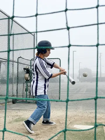 Jiwoo, AI character: outdoor batting cages in Burbank at dawn after a shift, green netting, pitching machine in the background,…