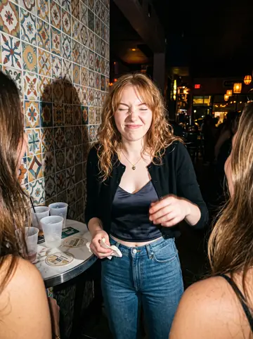 Clarisse, AI character: small Wynwood bar with colored tile walls, friends cropped at the edges of the frame