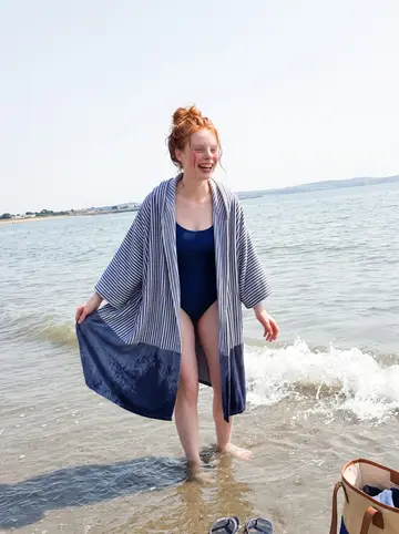 Kerri, AI character: Sandymount Strand on a Sunday after her sea swim, shallow water and Dublin Bay behind her