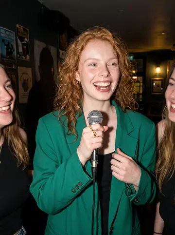 Kerri, AI character: Thursday karaoke night in a crowded Dublin pub with her flatmates cropped around the edges