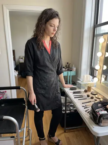 Katerina, AI character: small bridal prep room above a salon in Astoria, makeup chair and kit spread out beside the window