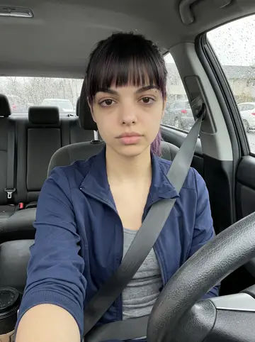 Mayelin, AI character: parked car outside the care home after a wet night shift, rain drops on the windshield