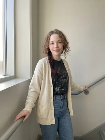 Siobhan, AI character: a quiet concrete stairwell at UMass Boston, late afternoon, one landing above the bookstore level where…
