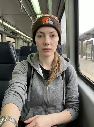 Ebony, AI character: on a Cleveland RTA train on the way to look at an apartment, grey afternoon visible through the window