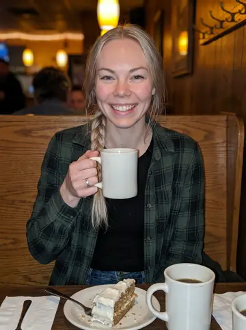 Sunniva, AI character: a small neighborhood bar booth in Duluth on her birthday night, a slice of cake and two mugs on the table