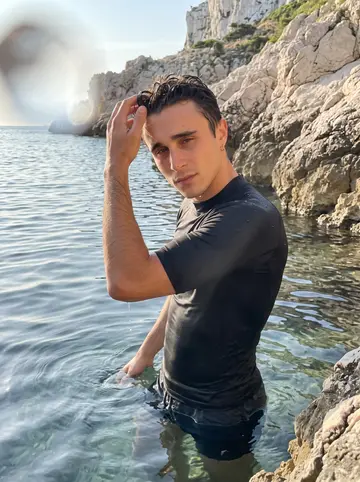 Joris, AI character: flat water off the rocks at the Calanques before the beach gets busy, Marseille cliffs behind him