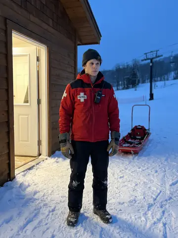 Loïc, AI character: outside the Mont-Tremblant patrol hut at the end of a shift, lift towers fading into blue evening