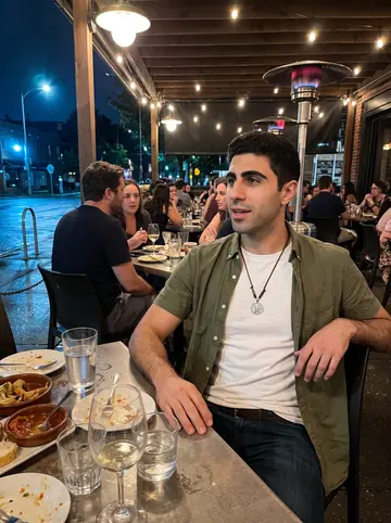 Adrián, AI character: a crowded patio at a casual tapas place after a late shift, wet pavement and string lights behind the table