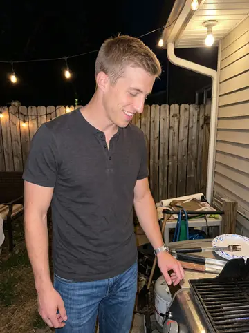Harrison, AI character: a neighbor's backyard cookout under string lights after a hot summer day
