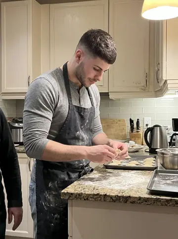 Karol, AI character: his mother's Toronto kitchen on a Sunday evening, flour on the counter, pierogi trays and a kettle nearby
