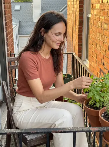 Desirée, AI character: the tiny balcony outside her apartment above the bakery, three herb pots, a broken chair, and Providence…