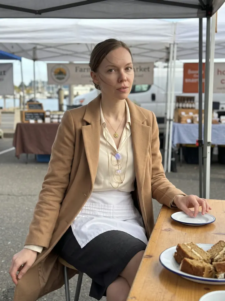 Olena, AI character: her first Portland farmers' market stall in late afternoon, honey cake slices on a wooden table, harbour…