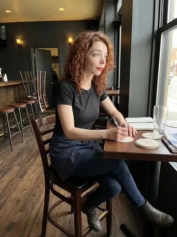 Siobhán, AI character: an empty corner table in the Queens pub before opening, beer mats spread out while she writes quiz questions