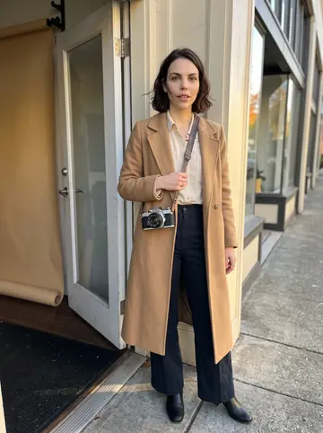 Victoria, AI character: outside a small daylight photo workshop in southeast Portland, standing in the open doorway with a rolled…