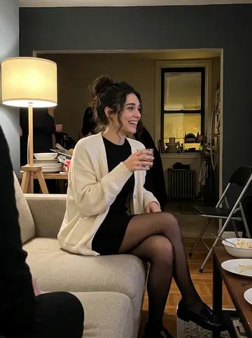 Ilaria, AI character: a crowded apartment living room after supper, folding chairs and plates stacked near the window