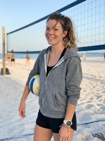 Sabrina, AI character: the sand volleyball courts on Clearwater Beach just after sunrise, Tampa Bay water pale blue behind her