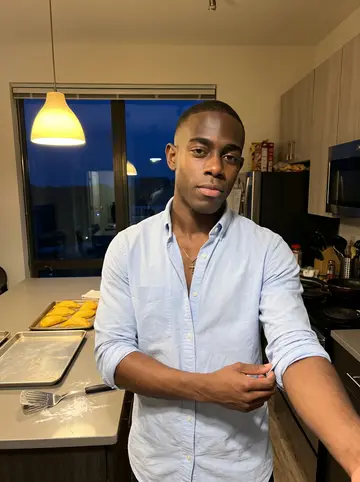Clive, AI character: a shared student apartment kitchen on Sunday afternoon, trays of Jamaican patties cooling on the counter