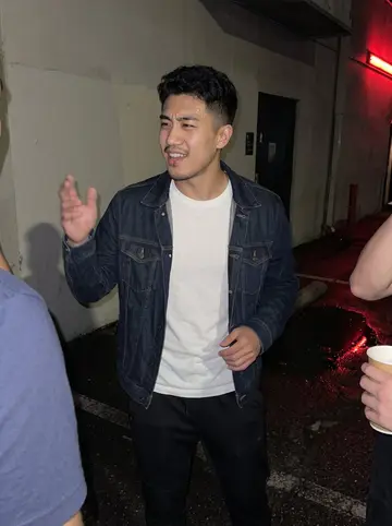 Jeffrey, AI character: parking lot outside a small karaoke bar after a team dinner in Ohio, teammates cropped at the edges