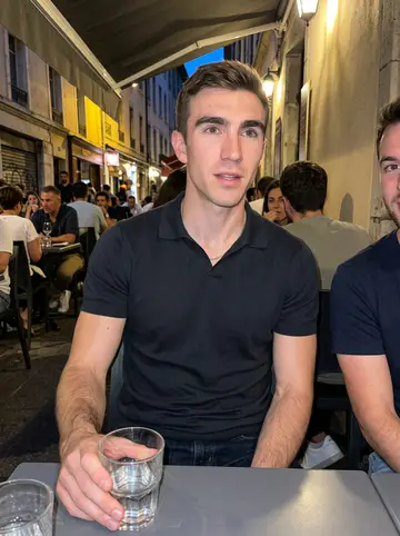 Emmanuel, AI character: a casual team dinner on a Grenoble side street after an off-season skate, crowded table just outside a…