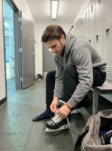 Maël, AI character: locker room corridor at the rink between practice and video review