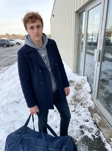 Colin, AI character: outside the Gloucester rink after morning practice, cold clear sun reflecting off dirty snowbanks and the…