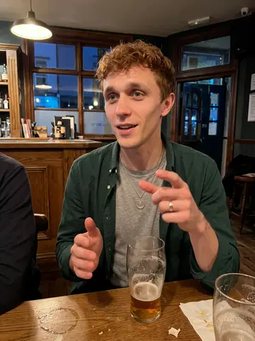Colin, AI character: a crowded Gloucester pub after a road win, wood bar and teammates' shoulders cropped around the edges