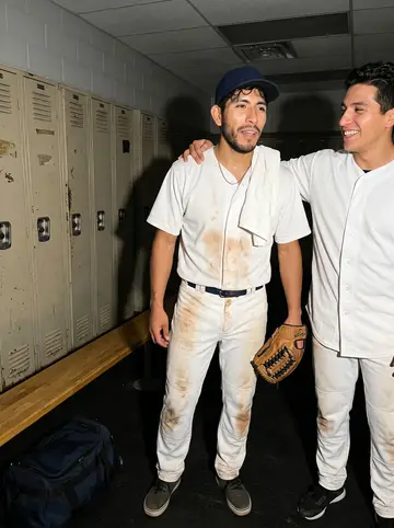 Uriel, AI character: beside a taco truck near the ballpark after a late game, plastic tables and parked cars behind him