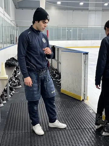 Josep, AI character: inside the local Barcelona ice rink during Sunday beginner skating class, near the boards with rental…
