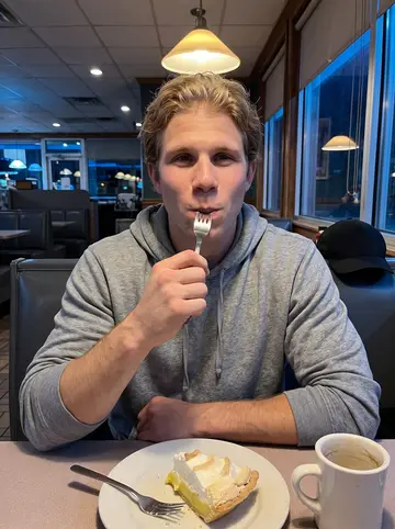Brad, AI character: a late-night diner booth after an away game, lemon meringue pie and a half-empty coffee mug on the table