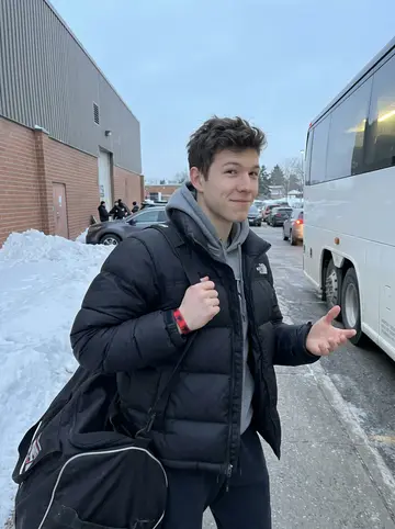 Mohamed, AI character: outside the Hamilton campus rink after Saturday practice, snowbanks along the parking lot and the team bus…