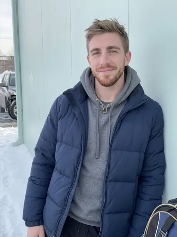 Landon, AI character: outside the Allentown ice rink after morning practice, leaning against the rink wall with his gear bag at…